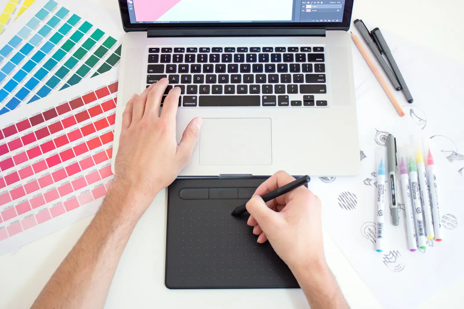 A designer sketching on a pen tablet beside colour swatches