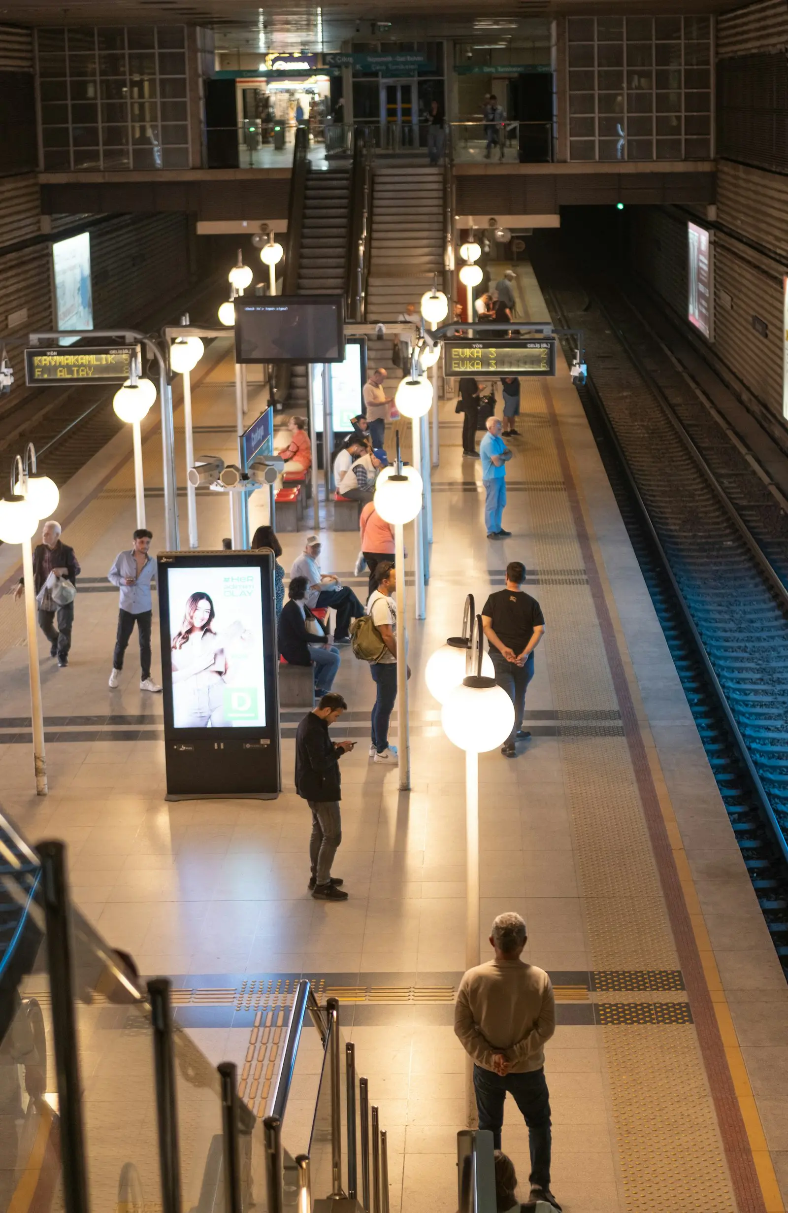 A digital ad totem on a busy metro platform